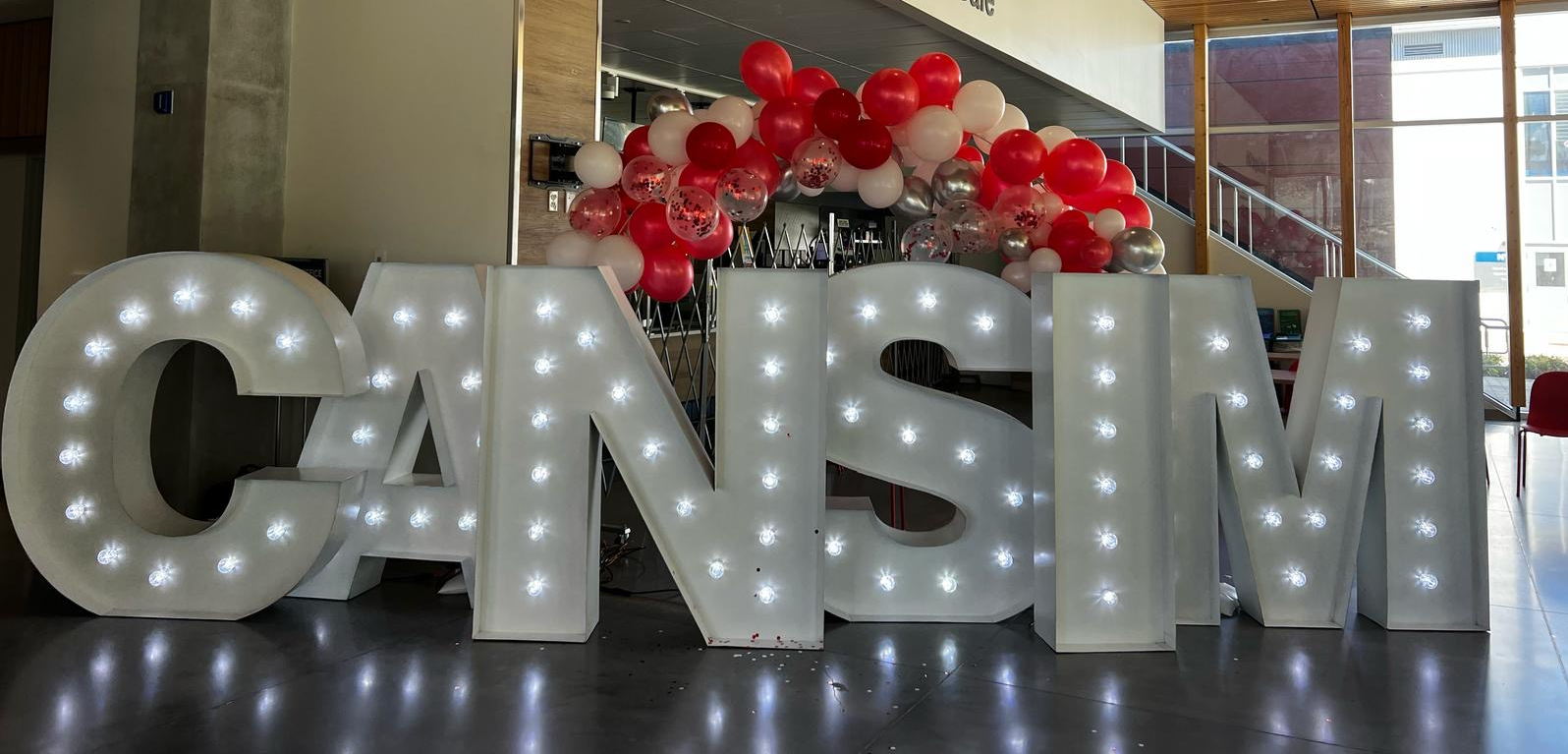 CAN-sim conference sign with lights and balloons