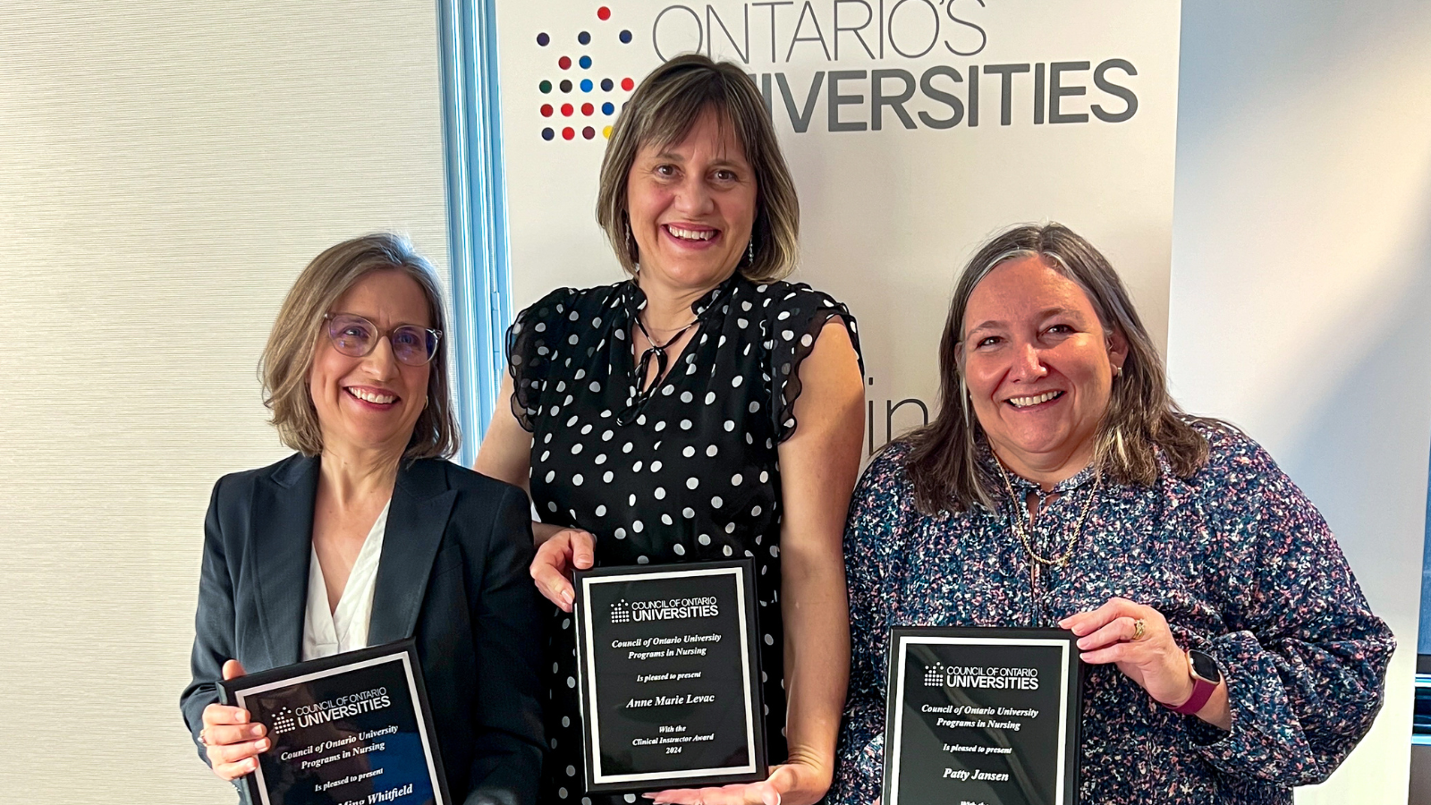 group shot of Dr. Martha Whitfield, Anne Marie Levac and Patty Jansen standing side by side in semi-formal dress, smiling into the camera and holding up their award plaques
