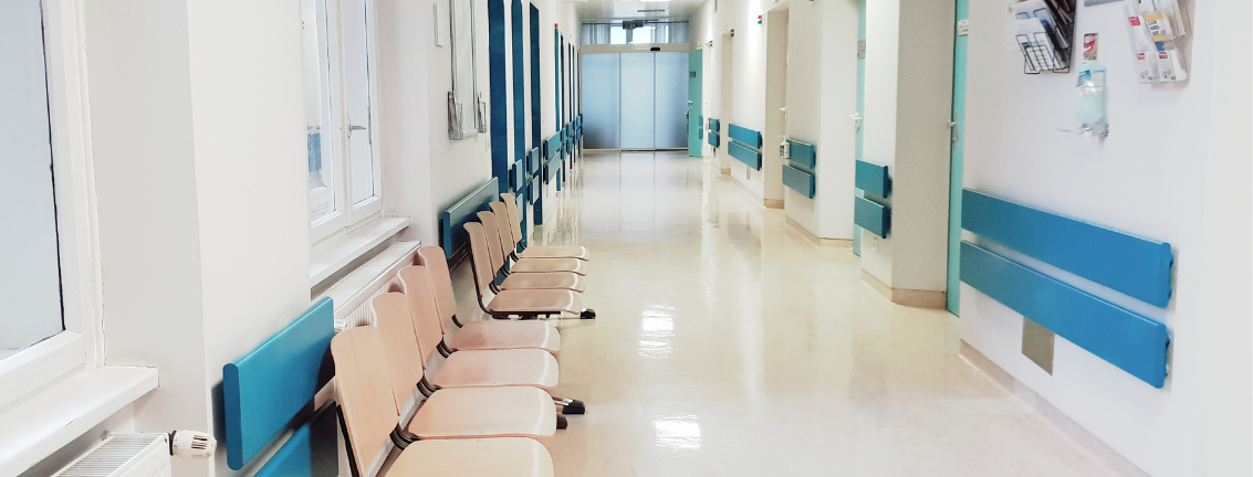 empty hospital hallway with a row of beige waiting room chairs. 