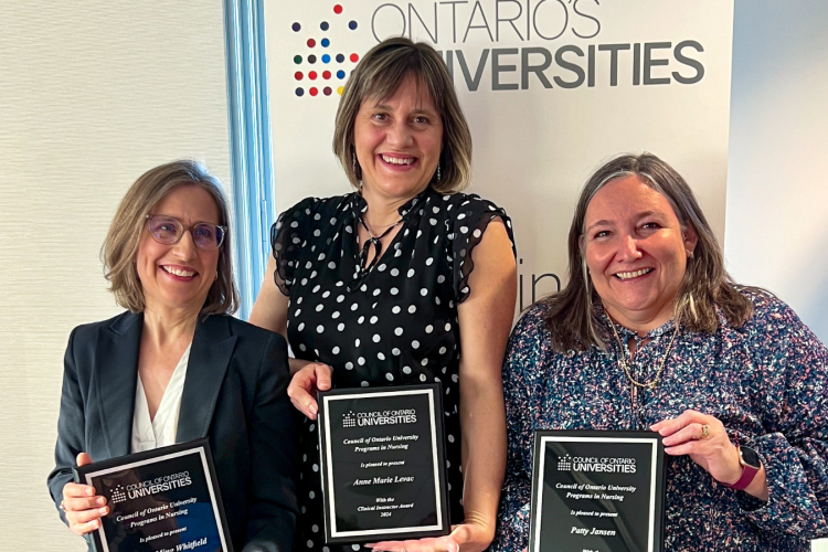 group shot of Dr. Martha Whitfield, Anne Marie Levac and Patty Jansen standing side by side in semi-formal dress, smiling into the camera and holding up their award plaques