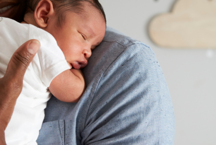 newborn sleeping on the shoulder of a man