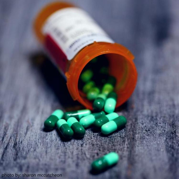 Green pills spilling from orange medication bottle