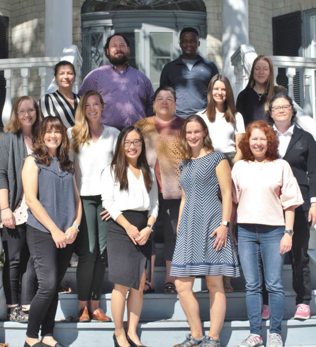 Queen’s Nursing graduate students, faculty, and staff pose together outside a campus building.